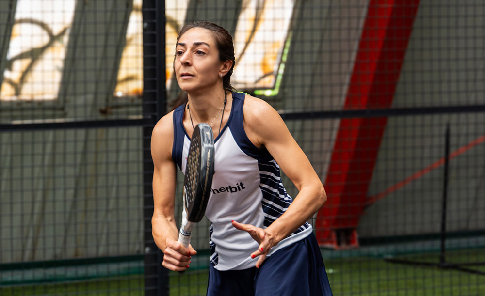 Allieva di padel in movimento sul campo indoor durante una lezione a Treviso