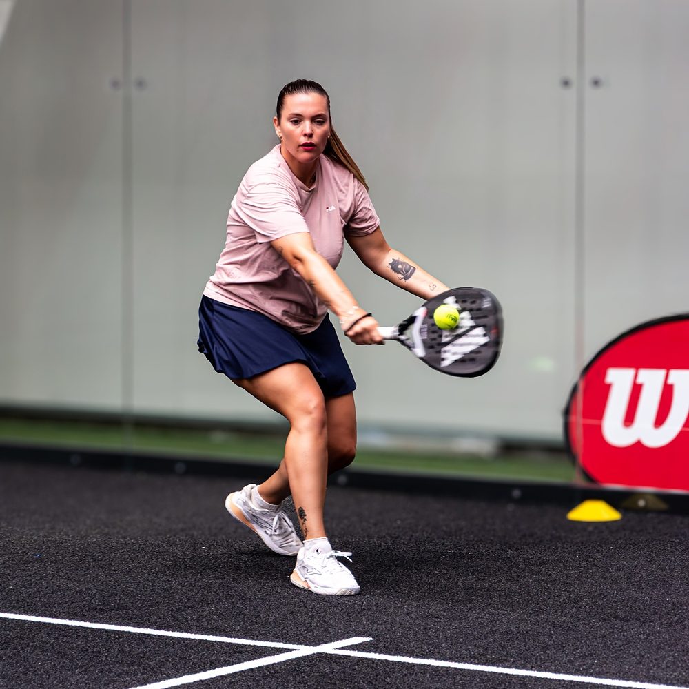 Allieva colpisce una palla bassa durante una lezione di padel femminile a Treviso