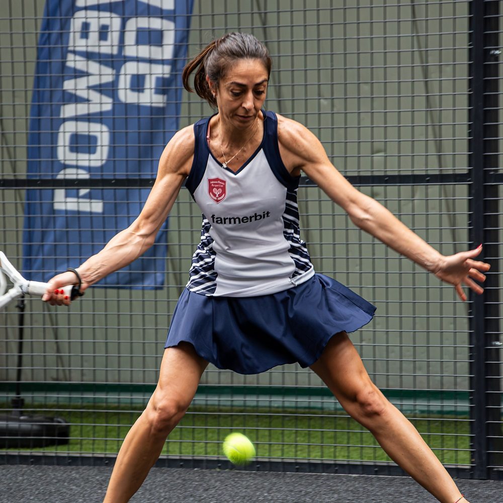 Giocatrice esegue un dritto in allungo sul campo da padel indoor a Treviso