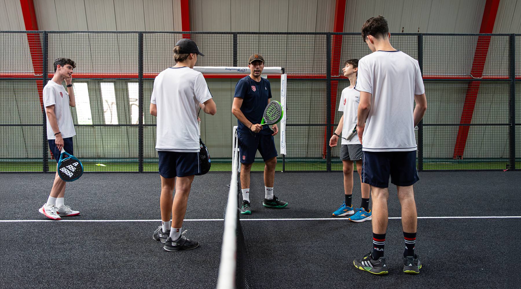 Maestro di padel durante una lezione del corso agonistico con quattro allievi sul campo indoor a Treviso