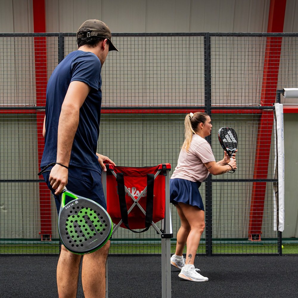 Maestro di padel affianca un'allieva durante un esercizio con il cesto a Treviso