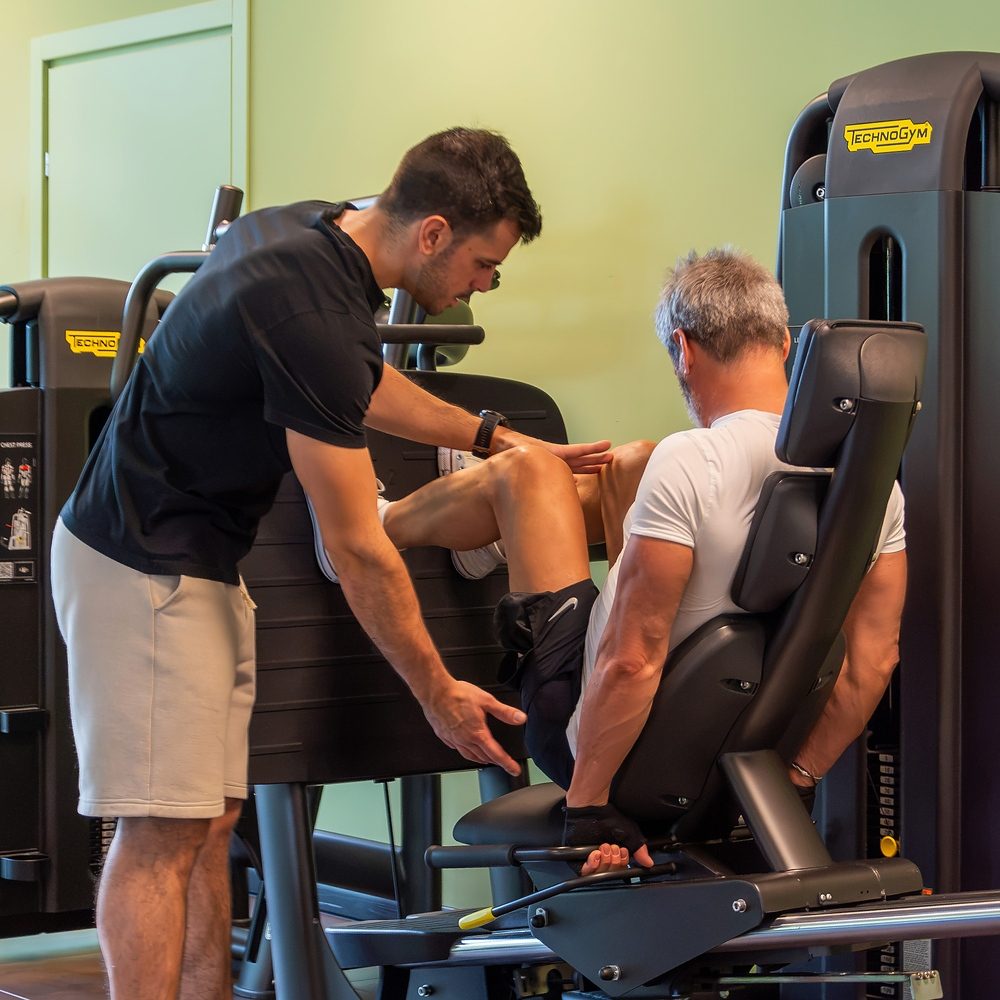 Personal trainer corregge l'esecuzione di un esercizio per le gambe a Treviso