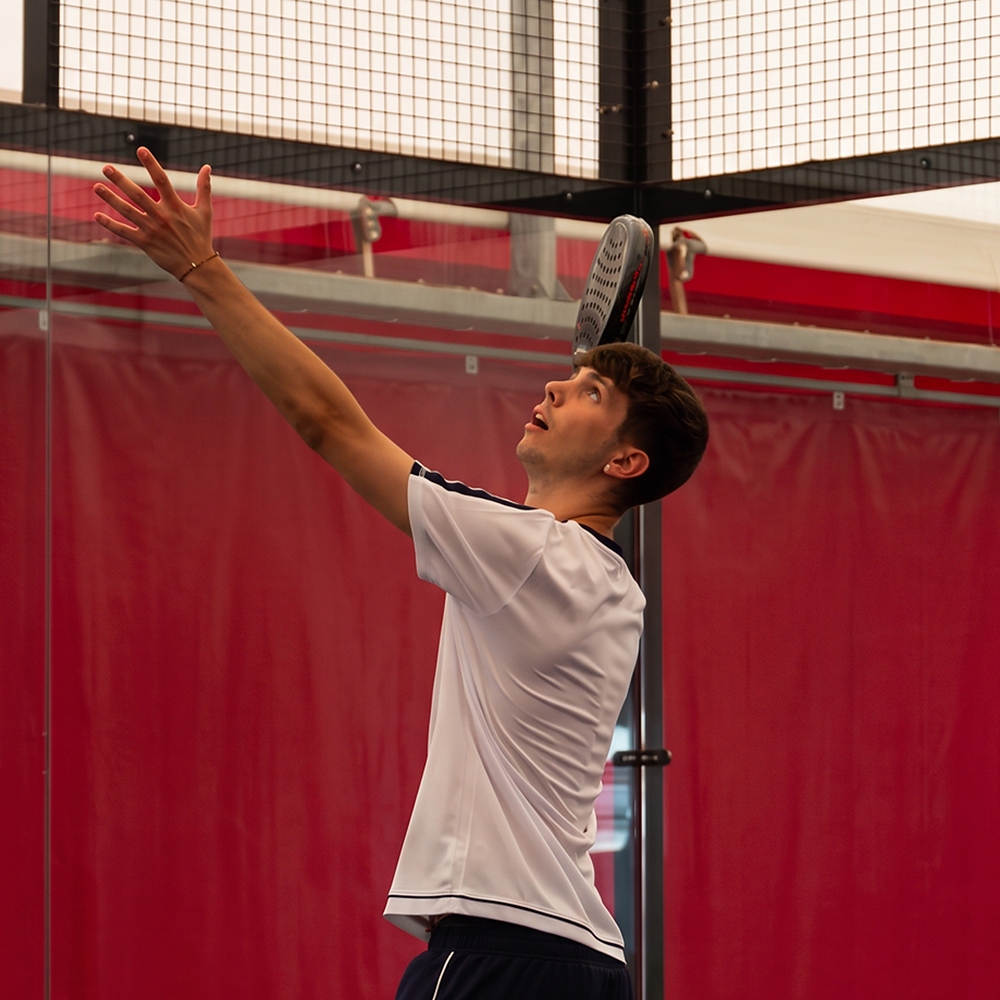 Giocatore esegue uno smash durante una partita di padel sul campo indoor a Treviso